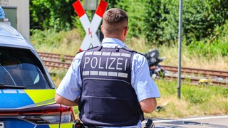 Ein Polizeibeamte am Unfallort. Der Autofahrer ist bei einem Zusammenstoß zwischen einem Zug und dem Auto in Gegnenbach (Ortenaukreis) gestorben.