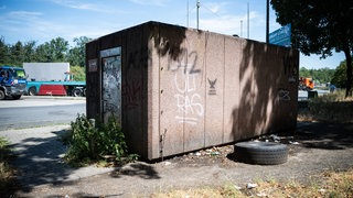 Ein verdrecktes Toilettenhaus an einer Raststätte mit Graffiti und Stickern. 