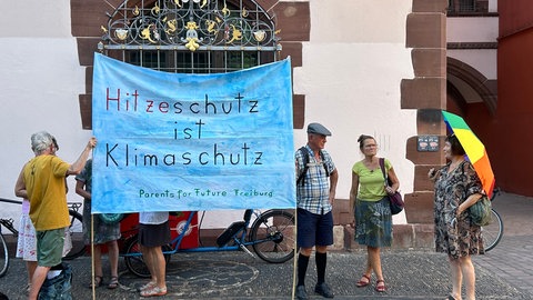 Mitglieder der Gruppe Parents for Future halten ein Banner hoch, auf dem steht: "Hitzeschutz ist Klimaschutz".