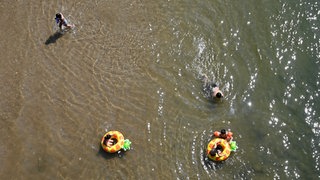 Kinder baden bei einer Temperatur von weit über 30 Grad an einer flachen Stelle eines Flusses.