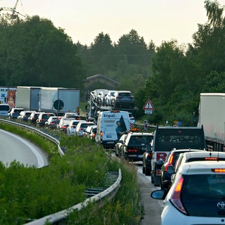 Smybolbild. Auf einer Autobahn stehen Lkw und Autos im Stau. 