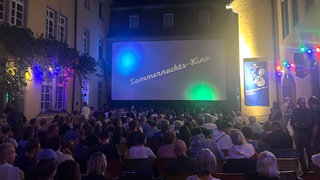 Menschen vor einer Leinwand im Innenhof des Schwarzen Klosters in Freiburg