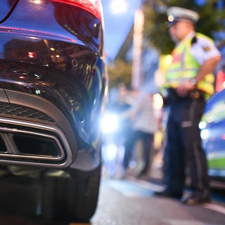 Symbolbild: Ein Polizeibeamter kontrolliert einen Autoposer. 