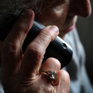 Eine ältere Frau mit einem Ring am Finger telefoniert. 