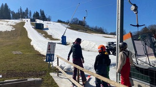 Drei Skisportler am Felderhaldelift in Isny. Rund um die Piste sind Teile des Berges grün