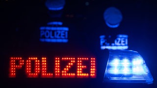 Zwei Polizisten stehen vor einem Polizeifahrzeug.