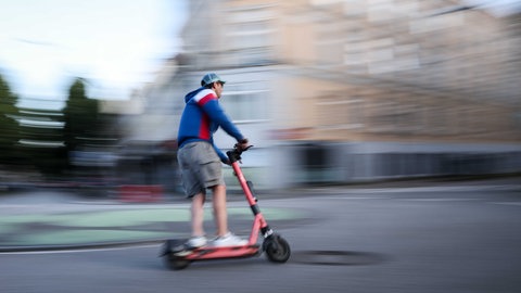 EIn Mann fährt auf einem E-Scooter. 