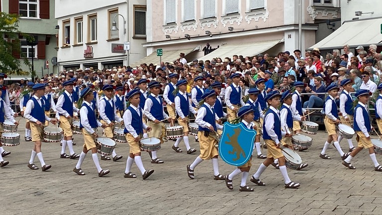 Kindergruppen laufen beim historischen Festumzug in blau-weißen Uniformen durch die Altstadt von Biberach