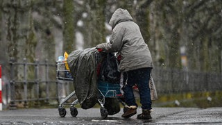 Ein Obdachloser schiebt bei Kälte einen Einkaufswagen. In der Region Bodensee-Oberschwaben gibt es in vielen Kommunen Hilfe für Menschen, die im Winter auf der Straße leben.