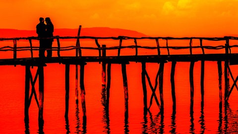 Ein Paar steht auf einer Holzbrücke im Sonnenuntergang. Der Bodensee ist Deutschlands beliebteste Kulisse für einen Heiratsantrag. (Symbolbild)