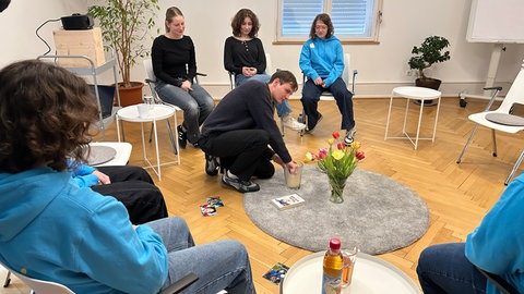 Eine Gruppe von jungen Menschen sitzt zusammen, ein junger Mann zündet eine Kerze an. Es ist eines der Geschwistertreffen, initiiert von Marian Grau. Er wird als "Student des Jahres 2026" ausgezeichnet.Marian Grau wird als "Student des Jahres 2026" ausgezeichnet.
