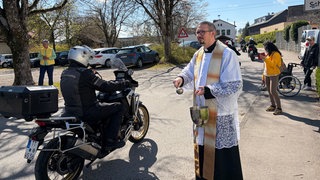 Ein Pfarrer segnet vorbeifahrende Motorradfahrer mit Weihwasser. In Laimnau holen sich am Ostermontag traditionell hunderte Biker den Segen für eine unfallfreie Motorradsaison.