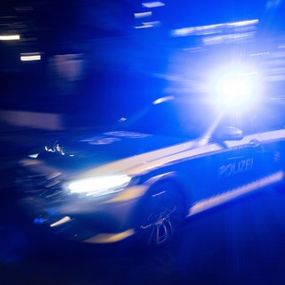 Ein Polizeifahrzeug fährt mit Blaulicht an einem Gebäude vorbei.