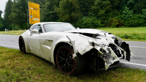 Der Sportwagen der Marke Wiesmann steht am Straßenrand. Die Schäden sind deutlich zu erkennen.