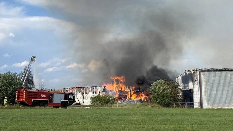 Ein Brand in einem Holzbetrieb bei Eberhardzell. Einsatzkräfte versuchen die Flammen zu löschen.