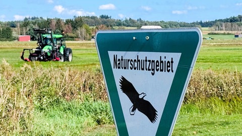 Naturschutzgebiet-Schild und Traktor