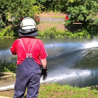 Feuerwehrmann blickt auf die Jagst - Mühlenbrand löste Fischsterben aus