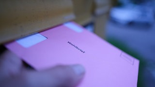 Stimmzettel werden in einen Briefkasten geworfen