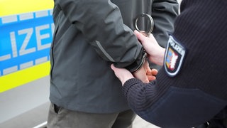 Ein Polizist legt einem Einbrecher Handschellen an (Symbolbild). Nach den Festnahmen von drei Männern ist die Zahl der Einbrüche in den Kreisen Heilbronn und Ludwigsburg zurückgegangen. 