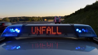 Auf einem Polizeifahrzeug warnt eine Leuchtschrift vor einer Unfallstelle - 2024 ist die Zahl der Verkehrstoten in RLP wieder gesunken.