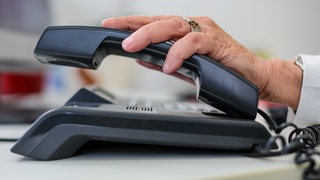 Eine Seniorin hält einen Telefonhörer (Symbol): Der Hitze-Service "Hitzetelefon" im Hohenlohekreis floppt. Gerade mal zwei Senioren haben sich diesen Sommer daür registiert.