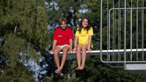 Die Schüler Leo und Marlene sitzen auf einem Sprungbrett im Freibad Nordheim.