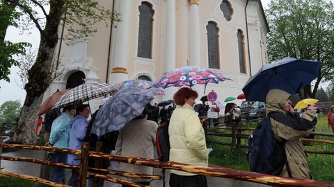 Hochzeitsgäste mit Regenschirmen vor einer Kirche (Symbolbild). Heiraten im November kann wettertechnisch eine Herausforderung sein.