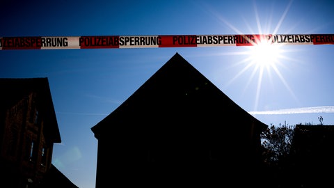 Ein Absperrband vor Häusern bei Nacht (Symbolbild). Die Staatsanwaltschaft hat den mutmaßlicher Mörder von Schöntal angeklagt. Er soll seine Schwiegermutter getötet haben. 