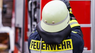 Ein Feuerwehrmann zieht einen Schlauch aus einem Löschwagen (Symbolbild). In ungewöhnlich kurzen Abständen musste die Feuerwehr zu Rettungseinsätzen in Gewässern ausrücken.