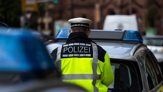 Ein Polizeibeamter steht zwischen zwei Einsatzfahrzeugen der Polizei (Symbolbild). Häufig werden Polizisten zu Unfällen gerufen, bei denen sie gar nicht gebraucht werden.
