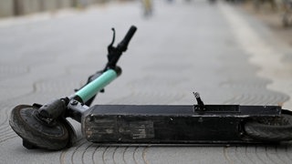 Ein E-Scooter liegt auf der Straße (Symbolbild). Immer wieder kommt es gerade bei Jugendlichen zu schweren Unfällen, teilweise enden sie tödlich.