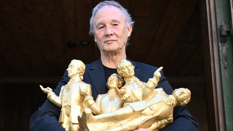 Der Wertheimer Konzeptkünstler Ottmar Hörl hält vier seiner goldenen Mozartskulpturen im Arm.