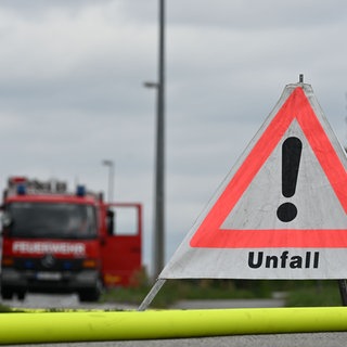 Ein Schild mit der Aufschrift "Unfall" steht vor einem Feuerwehrauto (Symbolbild). 