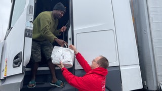 Thorsten Dossow von ver.di bringt dem Lkw-Fahrer Adam M. Essen vorbei.