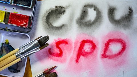 (Symbolbild): Auf einem weißen Blatt wurde mit Wasserfarbe in Schwarz "CDU" und in Rot "SPD" geschrieben. Nach der Bundestagswahl 2025 könnte die Regierung aus einer Koalition aus den beiden Parteien bestehen.