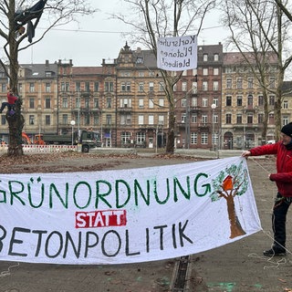Die Protestierenden haben Forderungen auf Laken geschrieben, die sie in die Platanen vor dem Badischen Staatstheater in Karlsruhe hängen. 