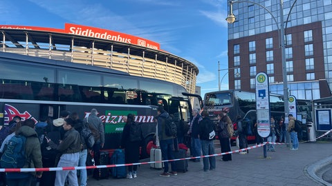 Reisende am Bahnhof in Baden-Baden stehen Schlange, um mit dem Schienenersatzverkehr weiterzufahren. 