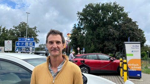 Börje Hilmer vor seinem Auto und Ladesäulen