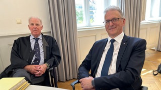 Bürgermeister Jürgen Troll (parteilos, rechts im Bild) sitzt mit seinem Anwalt im Gerichtssaal.