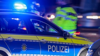 Ein Polizeiauto steht auf einer Straße. Es ist Nacht. Ein Mann läuft mit einer Warnweste hinter dem Auto entlang. Bei einem schweren Autounfall bei Rastatt ist Sonntagnacht eine 19-Jährige gestorben. 