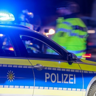 Ein Polizeiauto steht auf einer Straße. Es ist Nacht. Ein Mann läuft mit einer Warnweste hinter dem Auto entlang. Bei einem schweren Autounfall bei Rastatt ist Sonntagnacht eine 19-Jährige gestorben. 