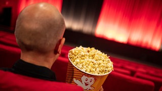 Eine Person sitzt mit einem Snack in einem Kino (Symbolbild).