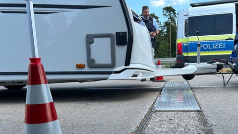 Ein Auto mit Anhänger rollt über die Wiegeblätter, damit die Polizei die Beladung prüfen kann
