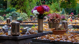 SymbolbildBlumen und Grablichter auf einem Friedhof