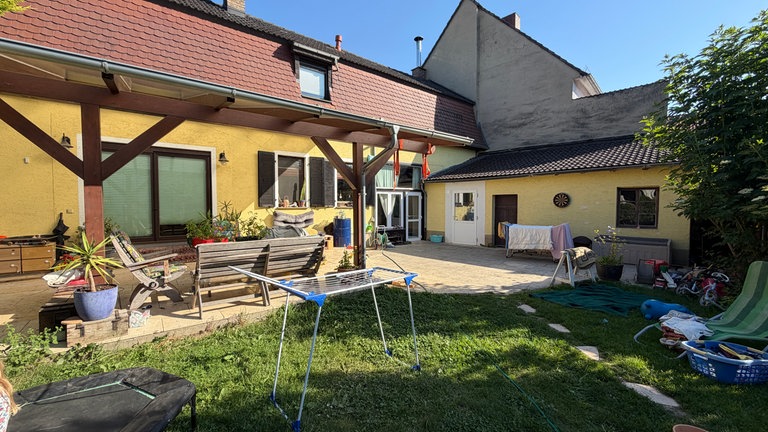 Das ehemalige Bauernhaus auf dem Gelände des Wohnprojektes Feldwinkel. Es gibt eine Gemeinschaftsterasse. Im Garten davor trocknet Wäsche.