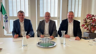Die Bürgermeister von Dossenheim und Schriesheim, David Faulhaber und Christoph Oehldorf, sowie Michael Lüer vom Projektentwickler PIONEXT unterschreiben Verträge.