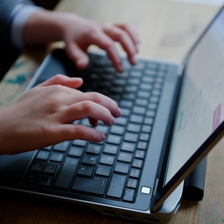 Kind schreibt etwas auf einem Laptop (Symbolbild)
