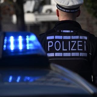 Ein Streifenwagen mit Blaulicht und Beamte der Polizei in Uniform:  Ermittler untersuchen das Tötungsdelikt an einer jungen Frau in Stuttgart. (Symbolbild)