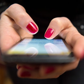 Eine Person tippt mit beiden Händen auf ihr Handy, Fingernägel sind rot lackiert. Ein Mann aus dem Rems-Murr-Kreis ist auf sogenanntes "Love Scamming" auf einer Dating Plattform reingefallen. Laut dem Polizeipräsidium Aalen hat er einer Person, die sich online als Notärztin ausgegeben hat, rund 2,3 Millionen Euro überwiesen. Kurz nach dem er das Geld überwiesen habe, brach die betrügerische Person den Kontakt ab. 