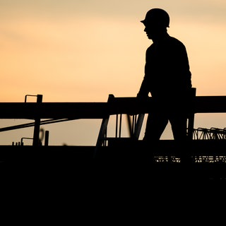 Die Silhouette eines Bauarbeiters zeichnet sich auf einer Baustelle vor dem verfärbten Morgenhimmel ab (Symbolbild). In holzgerlingen können junge Menschen bei einem Freiwilligen Handwerksjahr in verschiedene Handwerksberufe reinschnuppern. Das soll Orientierung bieten und führt vielleicht sogar zum Traumjob.